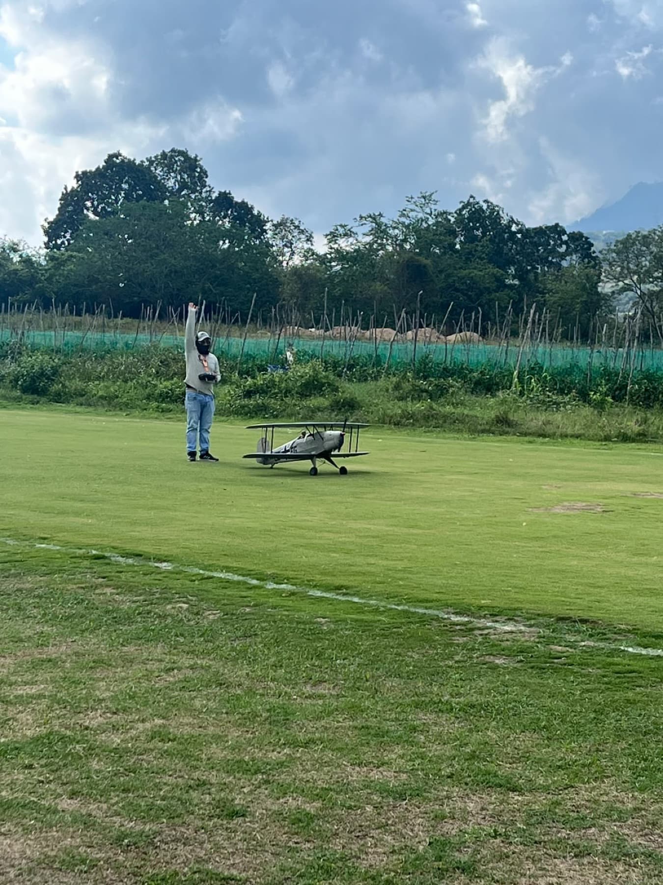 Un piloto levanta la mano en la pista junto a su biplano antes de despegar.