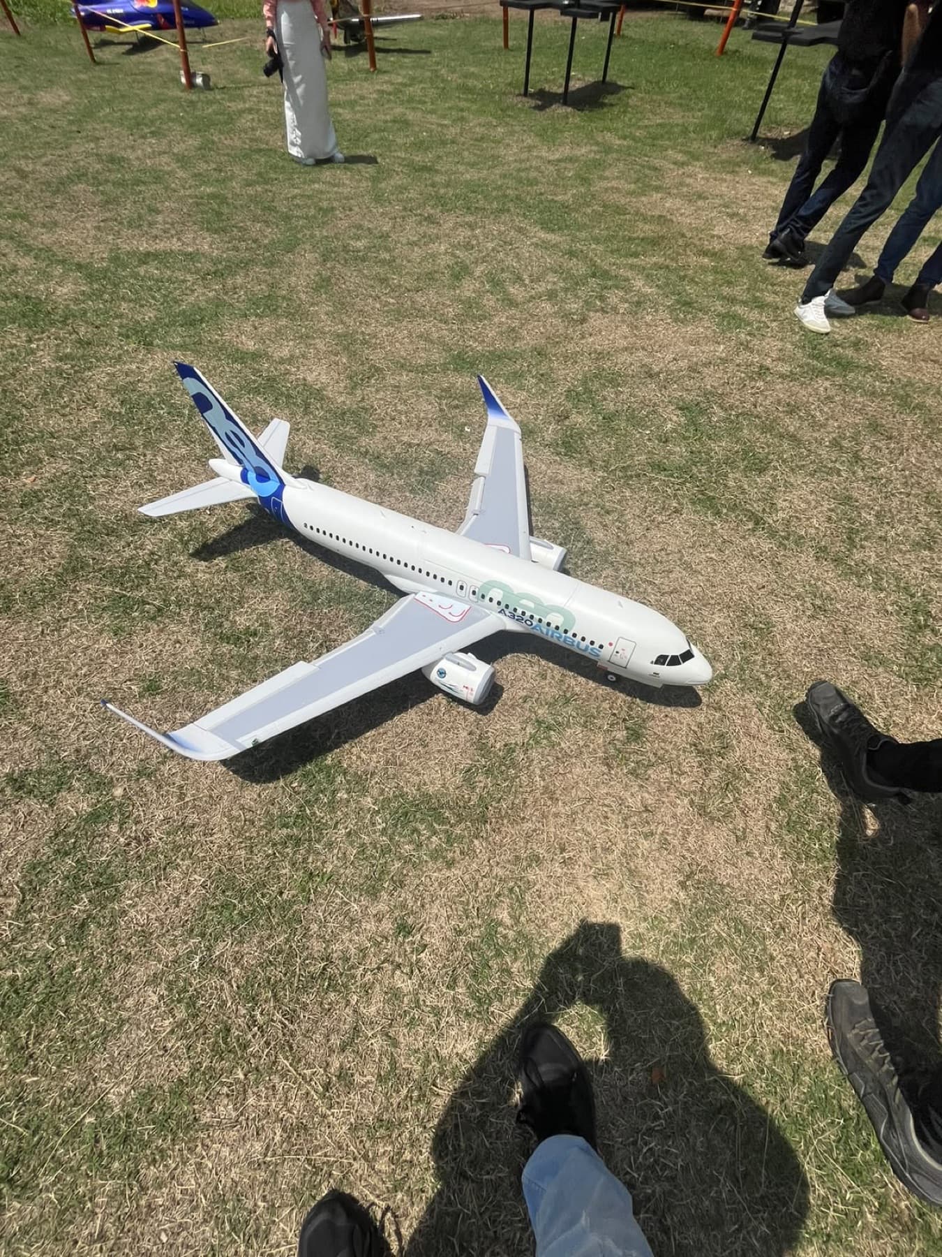 Réplica a escala de un Airbus A320 con la librea azul y blanca de Airbus, sobre el pasto del campo.
